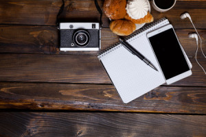 72434398 - camera with headphones with croissants and coffee next to notebook on wooden background
